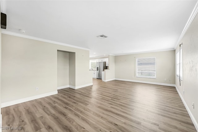 unfurnished living room featuring ornamental molding and light hardwood / wood-style flooring