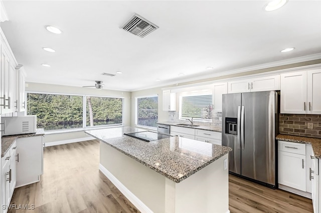 kitchen with light stone counters, stainless steel appliances, white cabinetry, and sink