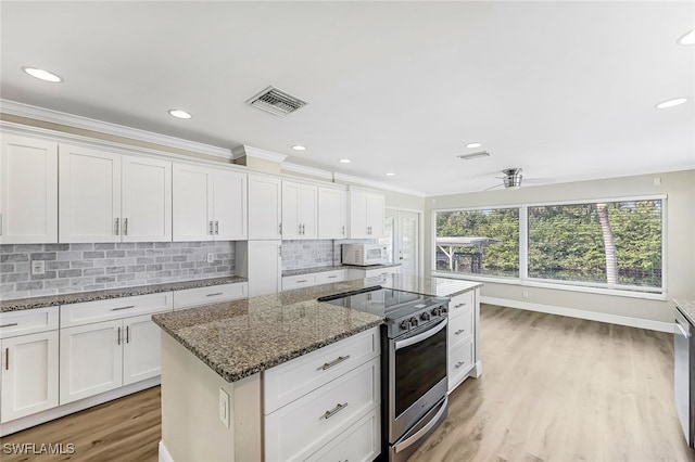 2199 Santiago Ave, Fort Myers, FL 33905 - kitchen featuring stainless steel range with electric stovetop, white microwave, backsplash, a ceiling fan, and white cabinetry