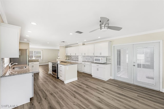 kitchen with light stone countertops, white cabinetry, stainless steel appliances, wood-type flooring, and ornamental molding