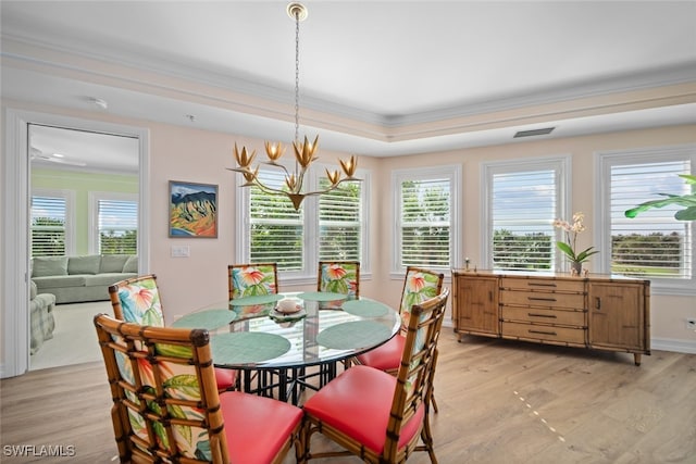 dining space featuring a chandelier, light hardwood / wood-style floors, a tray ceiling, and crown molding