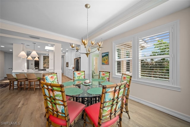 dining room featuring a notable chandelier, crown molding, and light hardwood / wood-style flooring