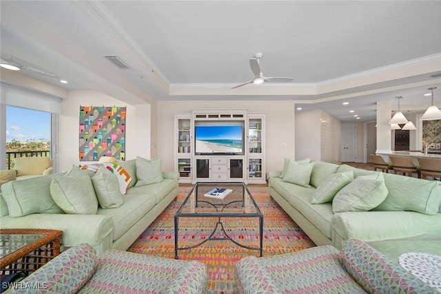 living room featuring ceiling fan, a raised ceiling, and crown molding