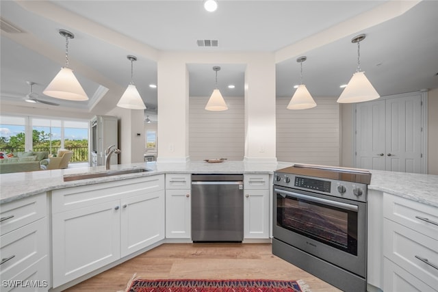 kitchen with white cabinets, sink, hanging light fixtures, light wood-type flooring, and appliances with stainless steel finishes