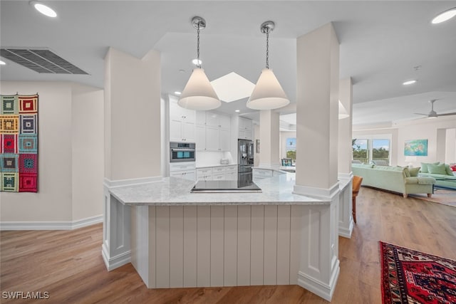 kitchen featuring light stone counters, light hardwood / wood-style flooring, white cabinets, and hanging light fixtures