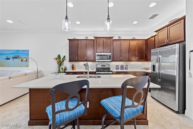 kitchen featuring sink, an island with sink, decorative light fixtures, a breakfast bar area, and appliances with stainless steel finishes