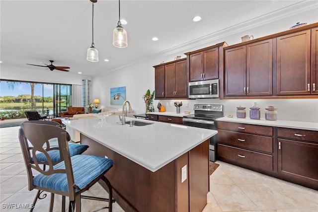 kitchen with a kitchen island with sink, ornamental molding, sink, and appliances with stainless steel finishes