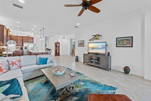 living room with ceiling fan, light tile patterned flooring, ornamental molding, and sink