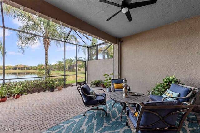 sunroom with ceiling fan and a water view