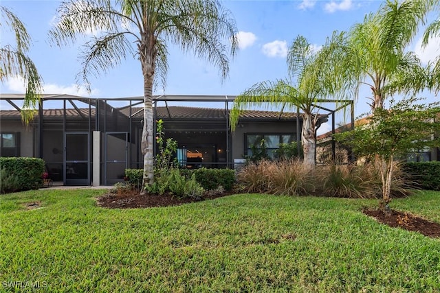 rear view of property with glass enclosure and a yard