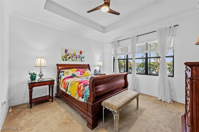 carpeted bedroom with a tray ceiling, ceiling fan, and ornamental molding