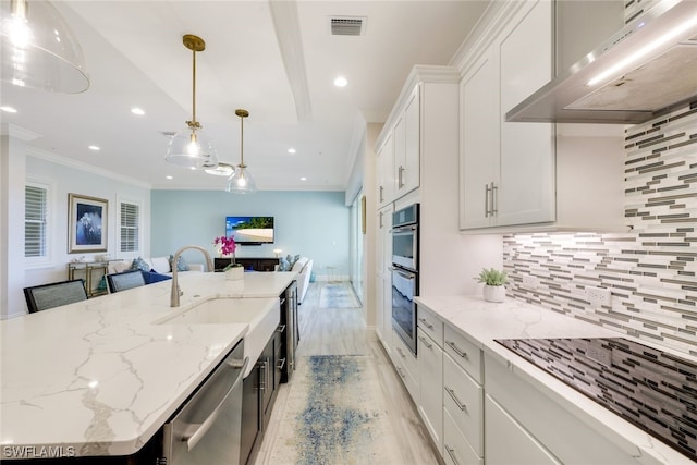 kitchen featuring pendant lighting, white cabinets, a center island with sink, wall chimney exhaust hood, and appliances with stainless steel finishes