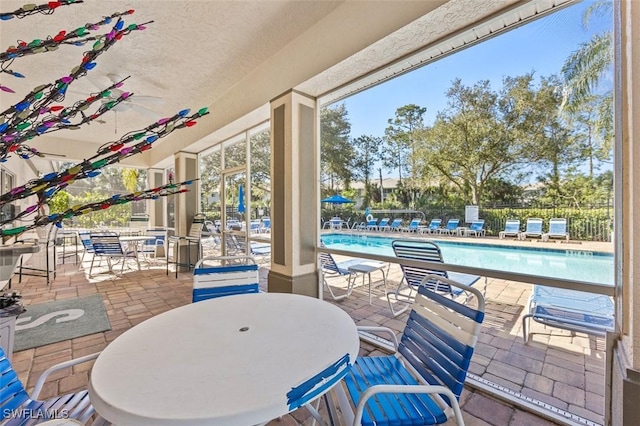 view of patio featuring outdoor dining space, fence, and a community pool