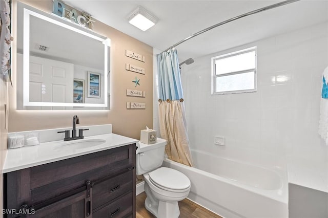 bathroom featuring toilet, wood finished floors, visible vents, vanity, and shower / bath combo