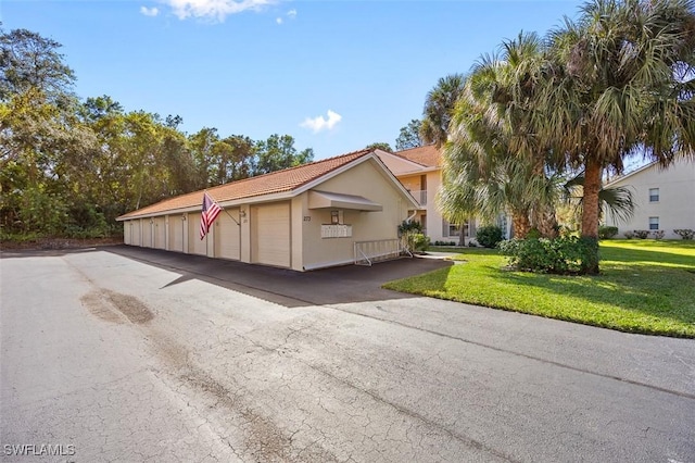 view of front of house featuring a front lawn, stucco siding, and community garages