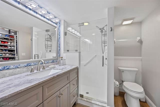 full bath with toilet, a wainscoted wall, a shower stall, and vanity