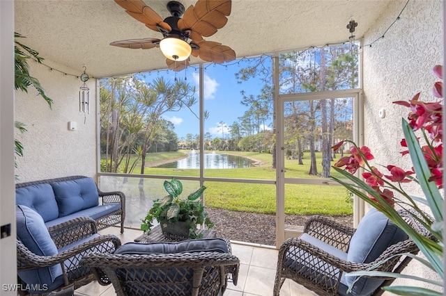 sunroom / solarium with a ceiling fan and a water view