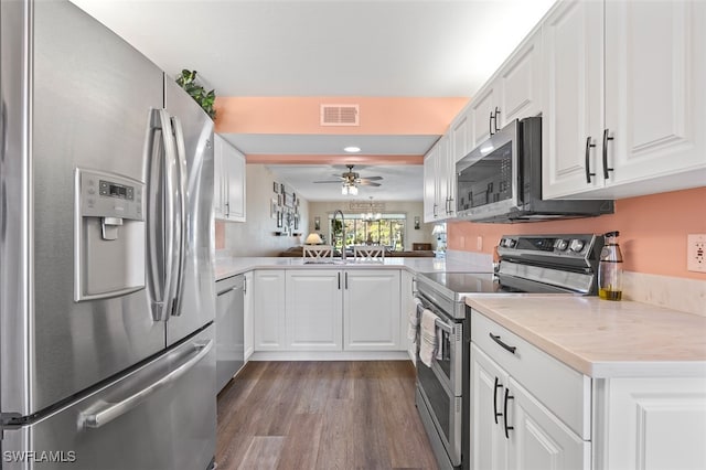 kitchen with white cabinets, sink, kitchen peninsula, wood-type flooring, and stainless steel appliances