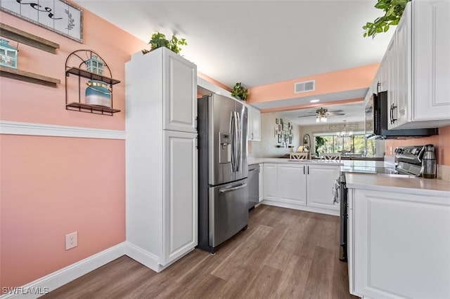 kitchen with appliances with stainless steel finishes, white cabinets, visible vents, and a sink