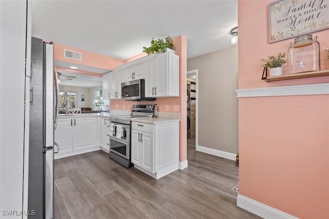 kitchen with visible vents, appliances with stainless steel finishes, white cabinets, and wood finished floors