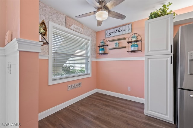 unfurnished dining area featuring dark wood-style floors, a ceiling fan, and baseboards