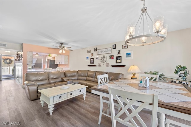 living room with dark wood-type flooring, visible vents, and ceiling fan with notable chandelier