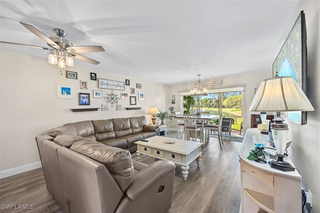 living area featuring baseboards, wood finished floors, and ceiling fan with notable chandelier