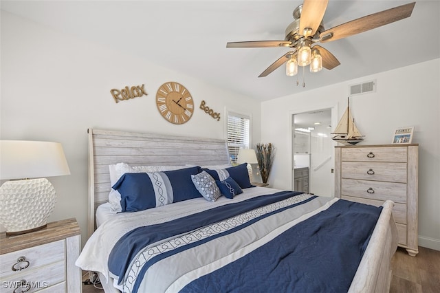 bedroom with visible vents, a ceiling fan, connected bathroom, wood finished floors, and baseboards