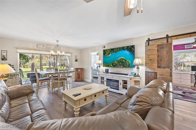 living room featuring a barn door, ceiling fan, and wood finished floors