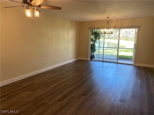 empty room with dark wood-style flooring, baseboards, and ceiling fan with notable chandelier