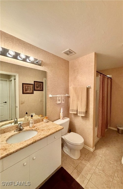 bathroom featuring vanity, tile patterned flooring, toilet, a textured ceiling, and walk in shower