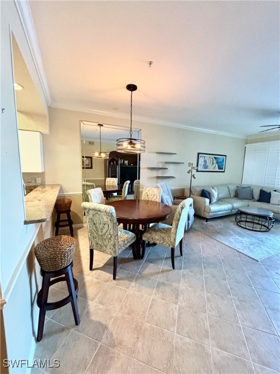 tiled dining space featuring ceiling fan and crown molding