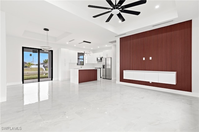 unfurnished living room with ceiling fan with notable chandelier, a raised ceiling, and wood walls