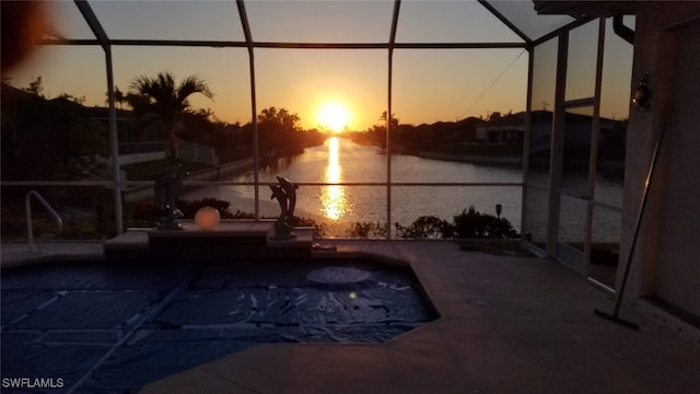 pool at dusk with a water view and a lanai