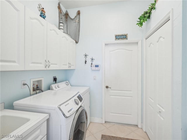 laundry area with cabinets, light tile patterned floors, sink, and washing machine and clothes dryer