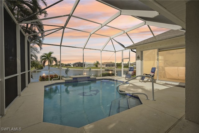 pool at dusk with a lanai, a water view, a patio, and a hot tub