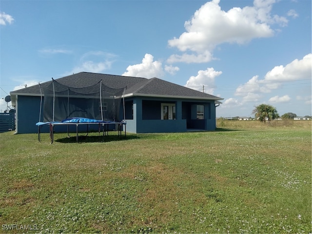 back of house with a yard and a trampoline