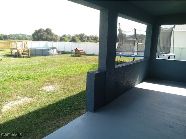 view of yard featuring a trampoline and a pool side deck