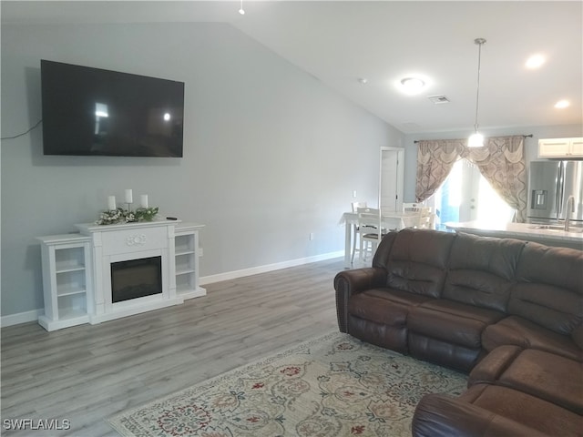 living room with sink, lofted ceiling, and hardwood / wood-style flooring