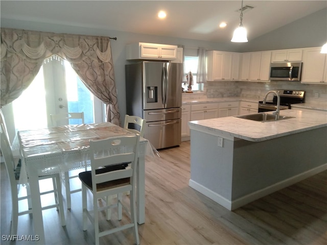 kitchen featuring kitchen peninsula, stainless steel appliances, pendant lighting, light hardwood / wood-style flooring, and white cabinetry