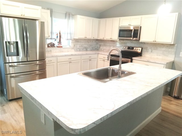 kitchen with tasteful backsplash, white cabinetry, light hardwood / wood-style flooring, and stainless steel appliances