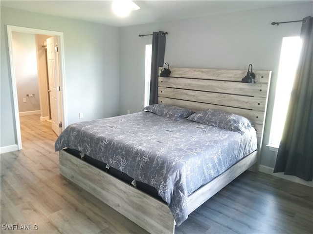 bedroom with ensuite bath and hardwood / wood-style floors