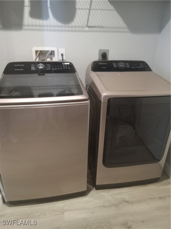 washroom with light hardwood / wood-style flooring and independent washer and dryer