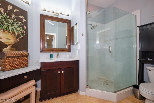 bathroom featuring tile patterned floors, vanity, a shower with shower door, and toilet