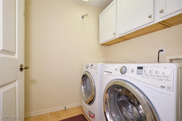 laundry area with washer and clothes dryer, cabinets, and tile patterned floors