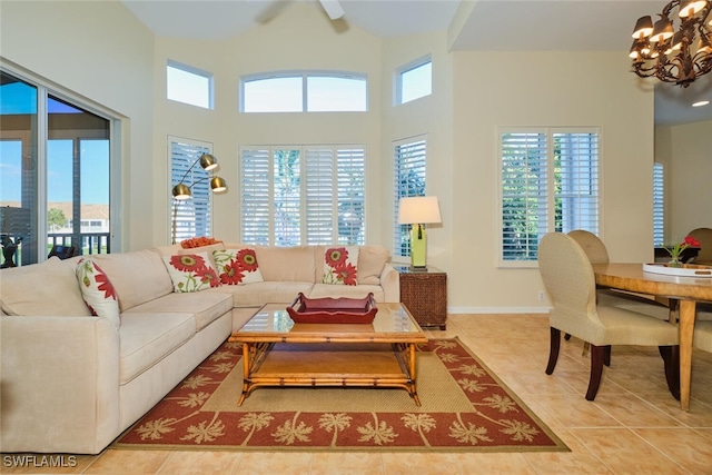 living room with light tile patterned floors, ceiling fan with notable chandelier, and a high ceiling