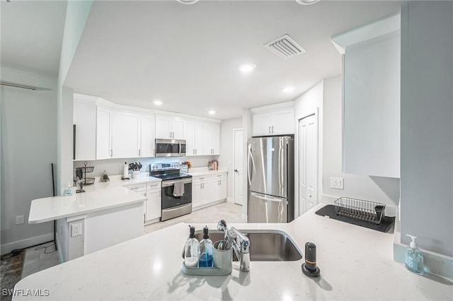 kitchen featuring sink, a breakfast bar area, white cabinetry, kitchen peninsula, and stainless steel appliances