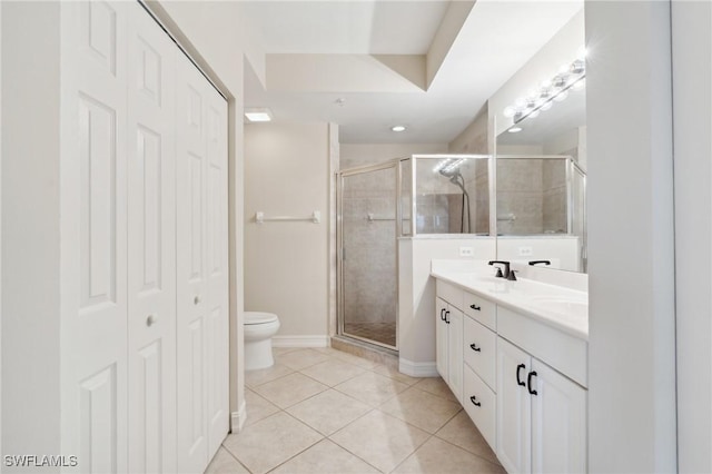 bathroom with baseboards, double vanity, a stall shower, tile patterned flooring, and toilet