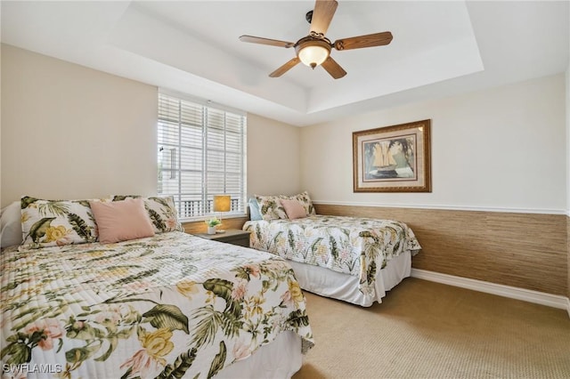 bedroom with a tray ceiling, ceiling fan, and light colored carpet