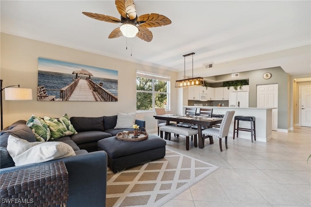 tiled living room with ceiling fan and crown molding